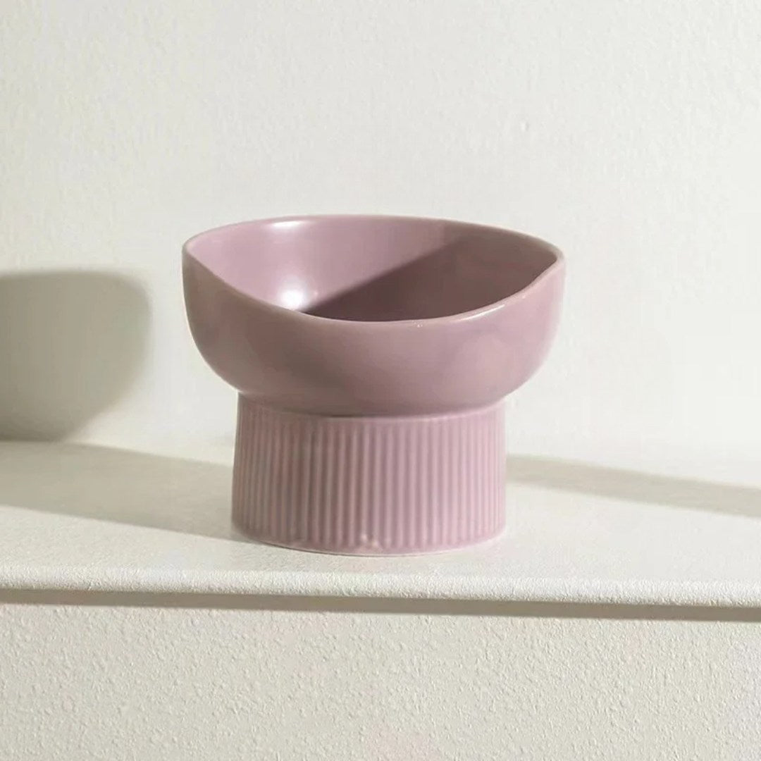 Pink ceramic cat bowl on a white surface with a light background