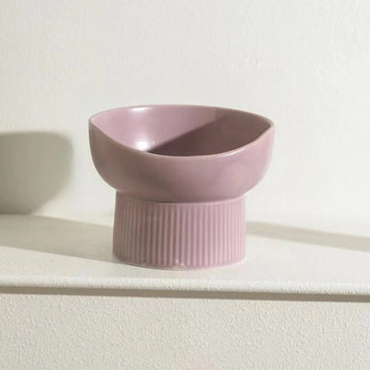 Pink ceramic cat bowl on a white surface with a light background