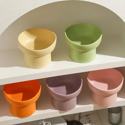 Set of colorful ceramic cat bowls on a shelf against a neutral background